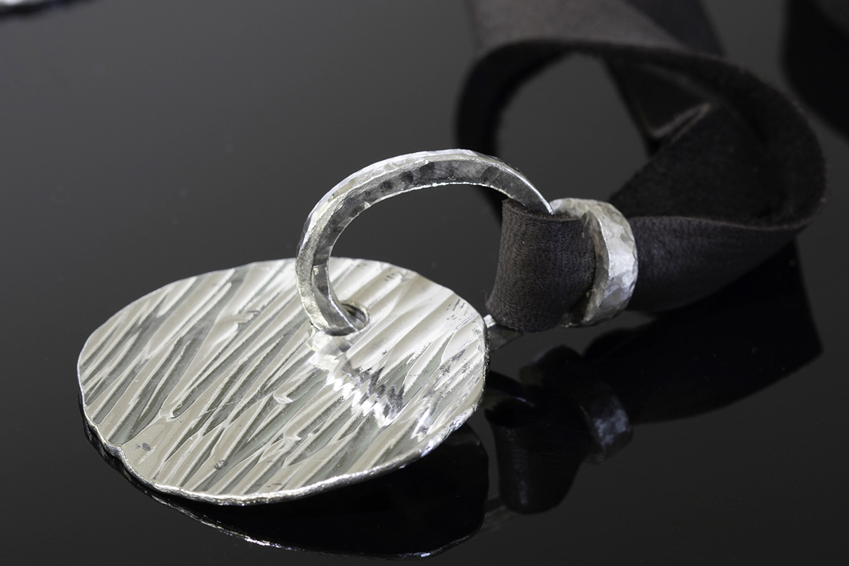 Silver pendant on table top.