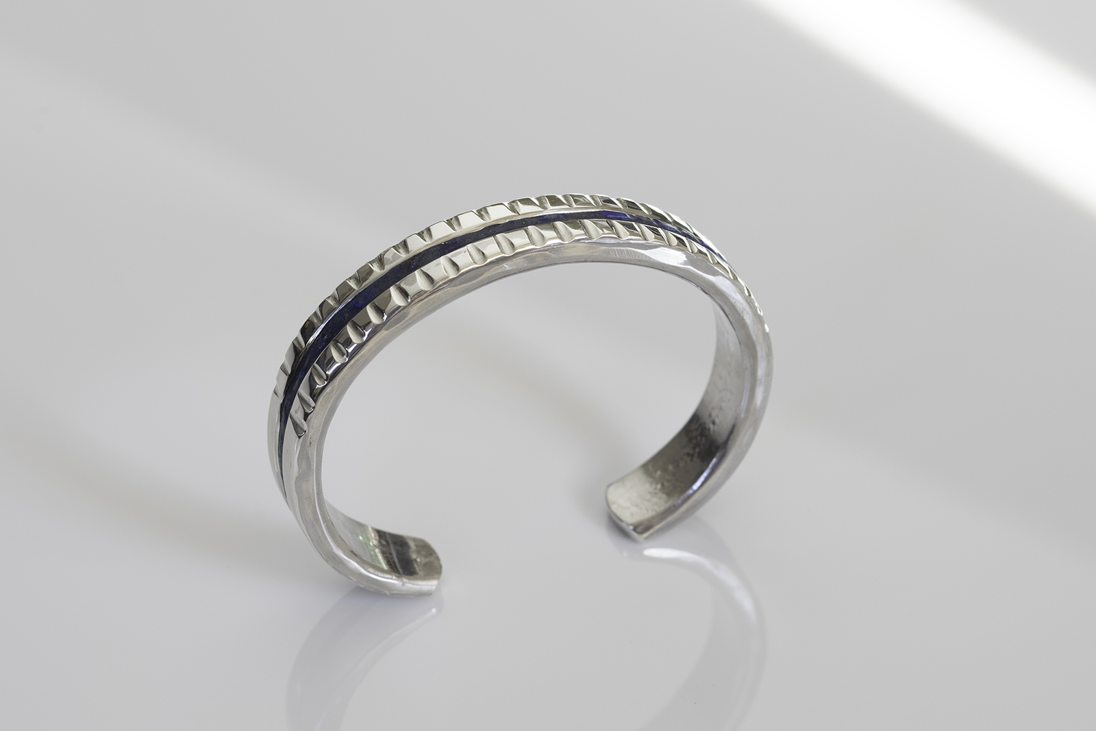 Lapis cuff on white reflective tabletop.