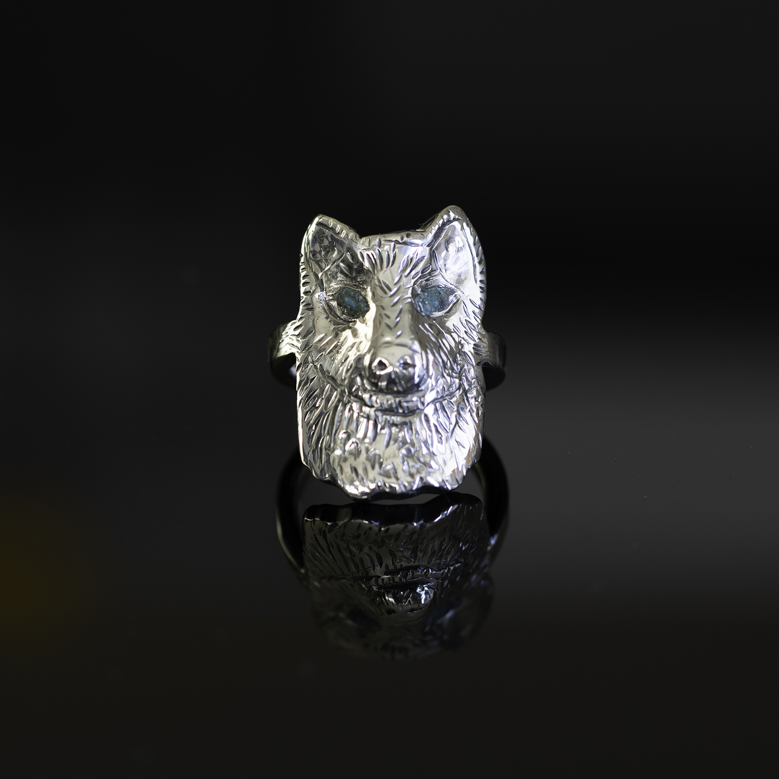 Wolf ring with blue eyes on reflective black background.